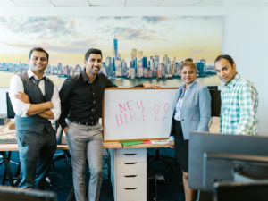 HR team standing with a sign that says "new hire".The