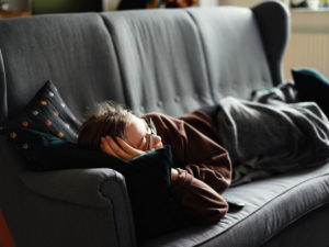 Woman laying on couch watching something. Learn how to get rid of your bad habits that are distracting you from success