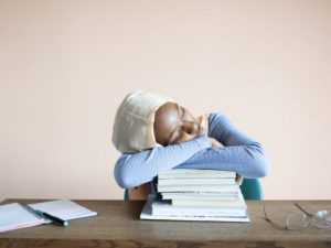 Lady laying on her arms on a stack of books. Here's how to handle study burnout