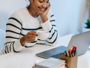 Woman sitting in front of her laptop, working. Here is why positivity is crucial in the workplace