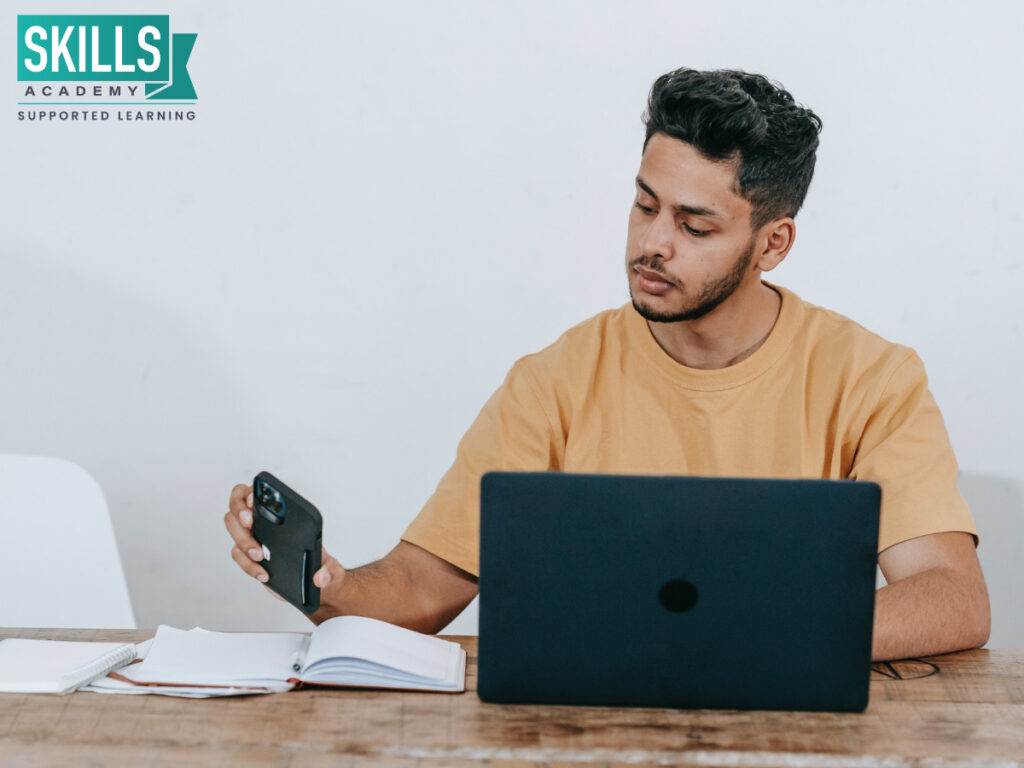 Student checking his phone while he is busy studying. Learn how to avoid digital distractions right here.