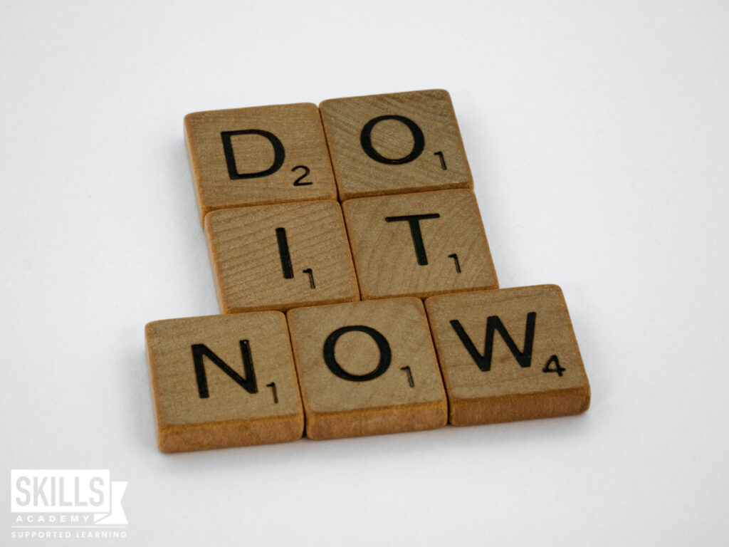 Wooden scrabble letters that tell spell out the words "do it now". Study with us today.