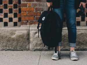 Student standing while holding a backpack in their hand. Find out where to study distance learning in South Africa.