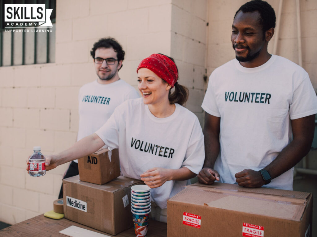 Volunteers standing at a table filled with boxes handing out small bottled water. Take a look at some of the hobbies you can add to your CV.