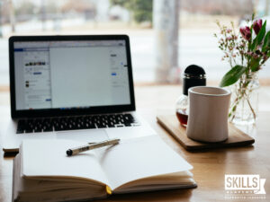 A neat home office space with notebook and pen, laptop and tea mug. Learn how to work from home successfully with us.