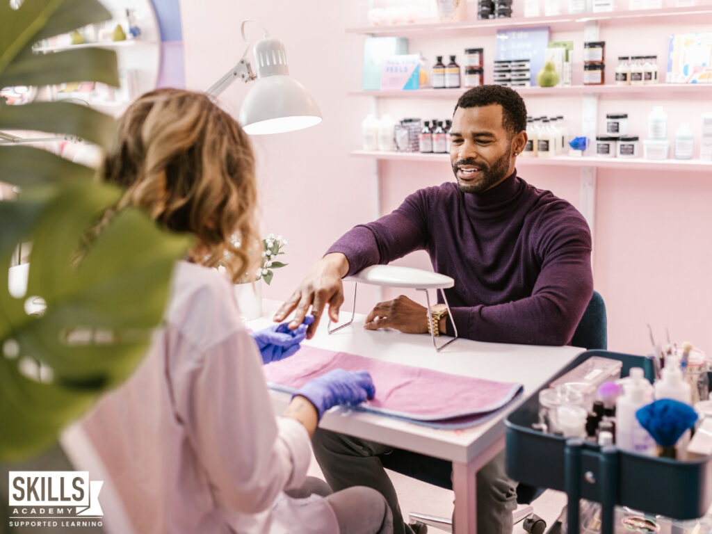 A beauty therapist giving a man a manicure after finding out why you should choose a career in beauty therapy. Study our beauty courses today.