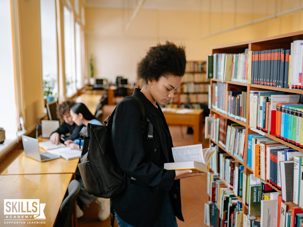 Student reading a book in a library. Find the courses you can study in 6 months with us right here.