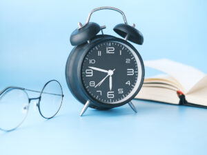 Clock next to a book and reading glasses. Here you will find our courses you can study in 6 months.