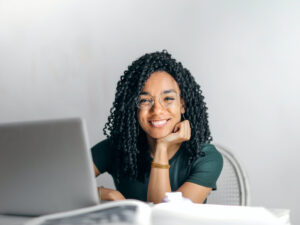 Lady behind a laptop smiling at the camera. Courses to Boost Your Office Career