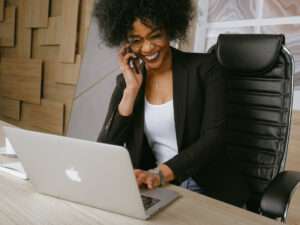 Lady on a phone call, working on her laptop at work. Creative ways to manage your duties at work.