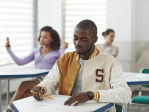Guy sitting at his desk in class. Questions to ask the college before you enrol