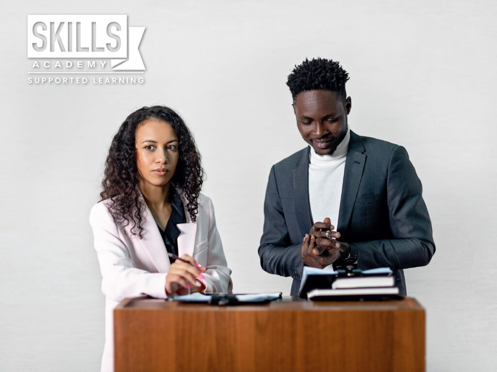 Two people standing behind a table. Tips on how to write a motivational letter.