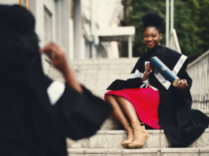 Girl sitting on stairs, taking photos with her degree. Courses That Offer Exemptions