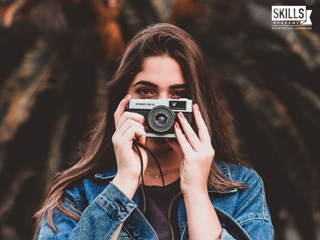 Girl holding a camera up to her face. Photography Courses you can Study Online