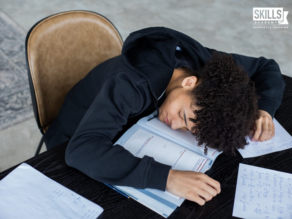 Guy sitting at his desk while his head rests on his books. Ways to Deal With Academic Burnout