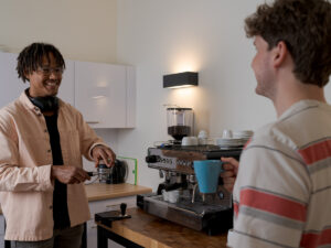 Two guys standing acress each other making coffee. Accredited Management Courses