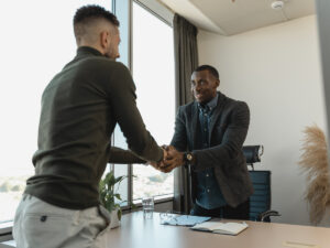 Two guys shaking hands in an interview room. How to Talk About Your Weaknesses in an Interview