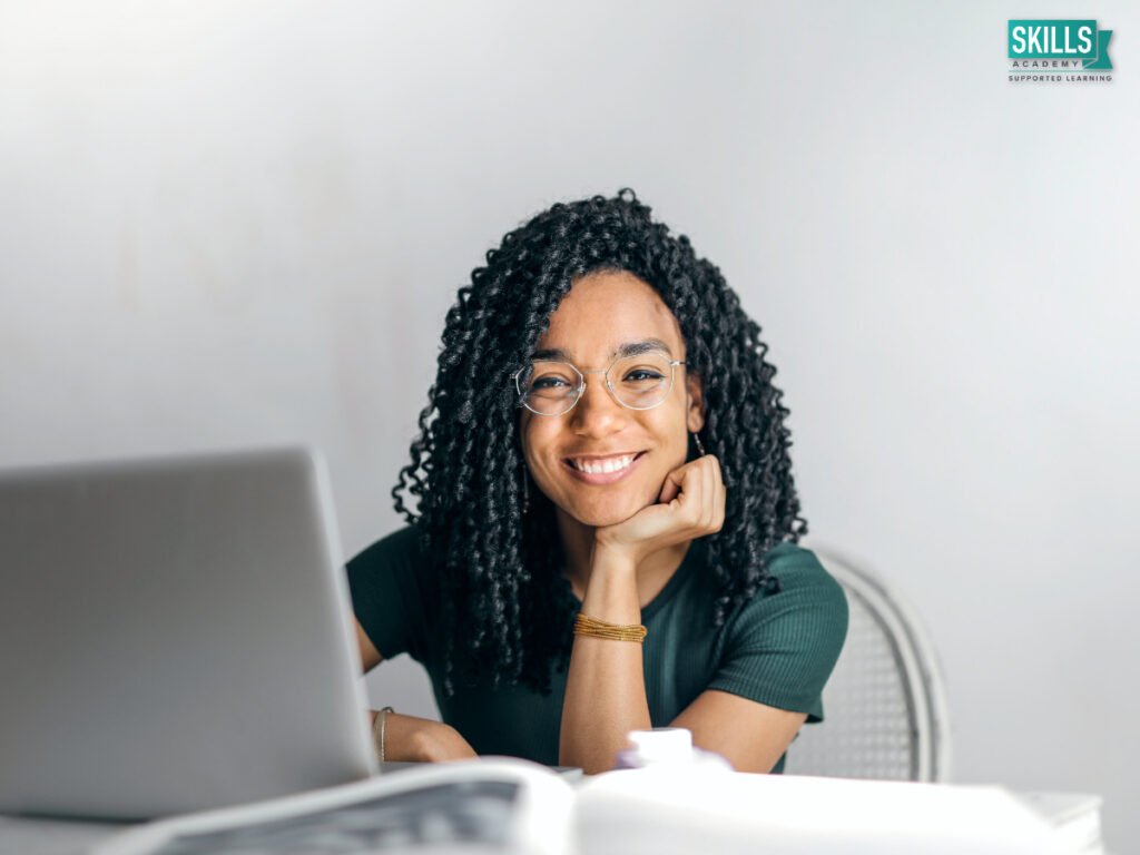 Woman sitting behind a laptop smiling. Business Management Diploma Courses.