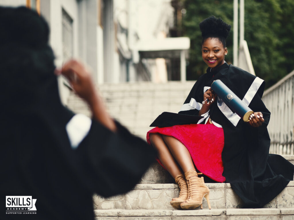 A recent graduate sitting on her college's steps being photographed with her diploma. Can you complete ICB courses in one year? Find out more right here.