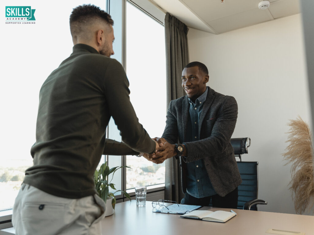Two business men shaking hands across the table in an office. Get clued up on career options with ICB courses right here.
