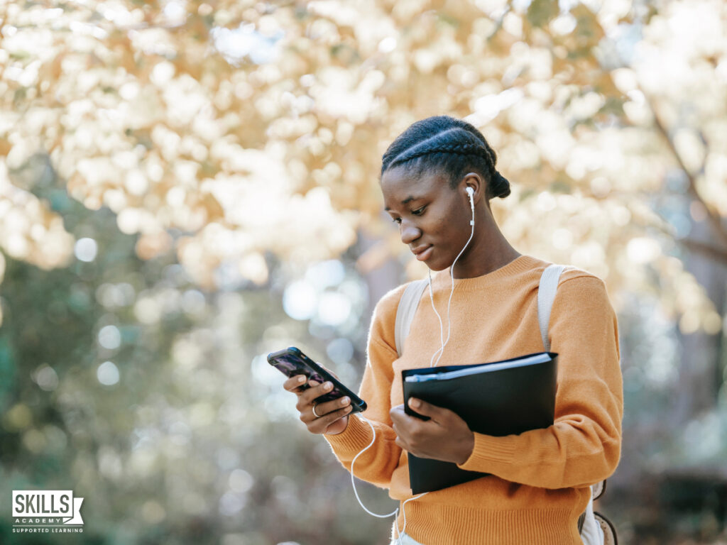 Student holding a file and looking at her cellphone. Find out more about our matric equivalent ICB Courses right here.