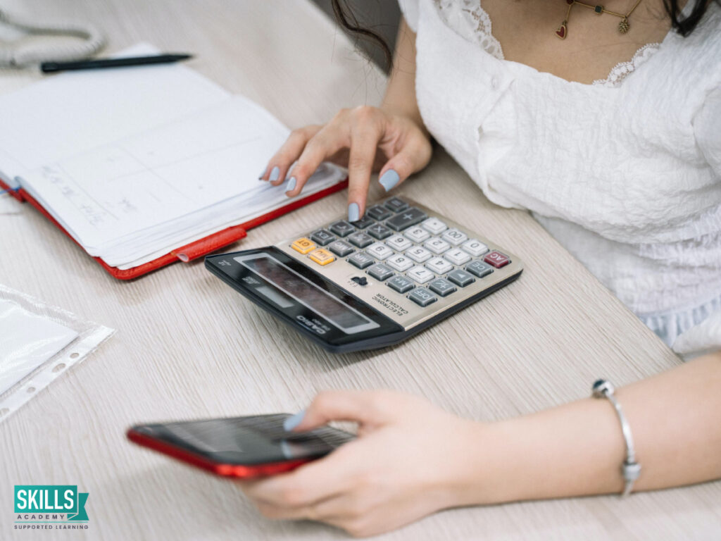 Student using acellphone and calculator tos tudy accounting online. Enroll with us today!
