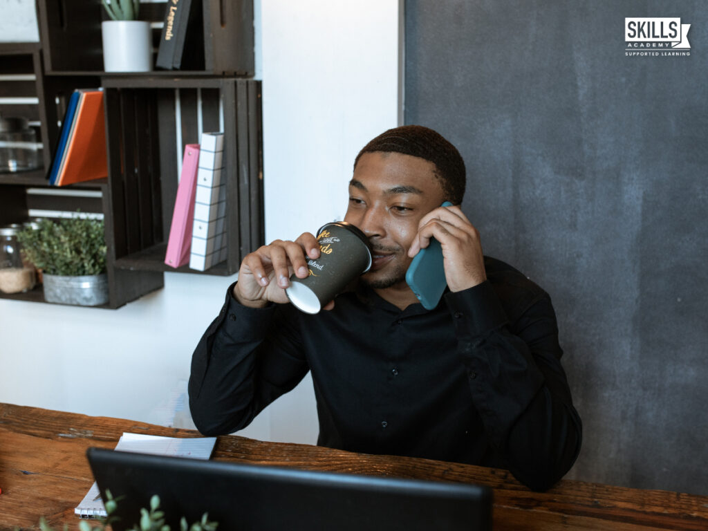 Guy drinking a coffee while on the phone. Where to Study Office Administration Online in South Africa.