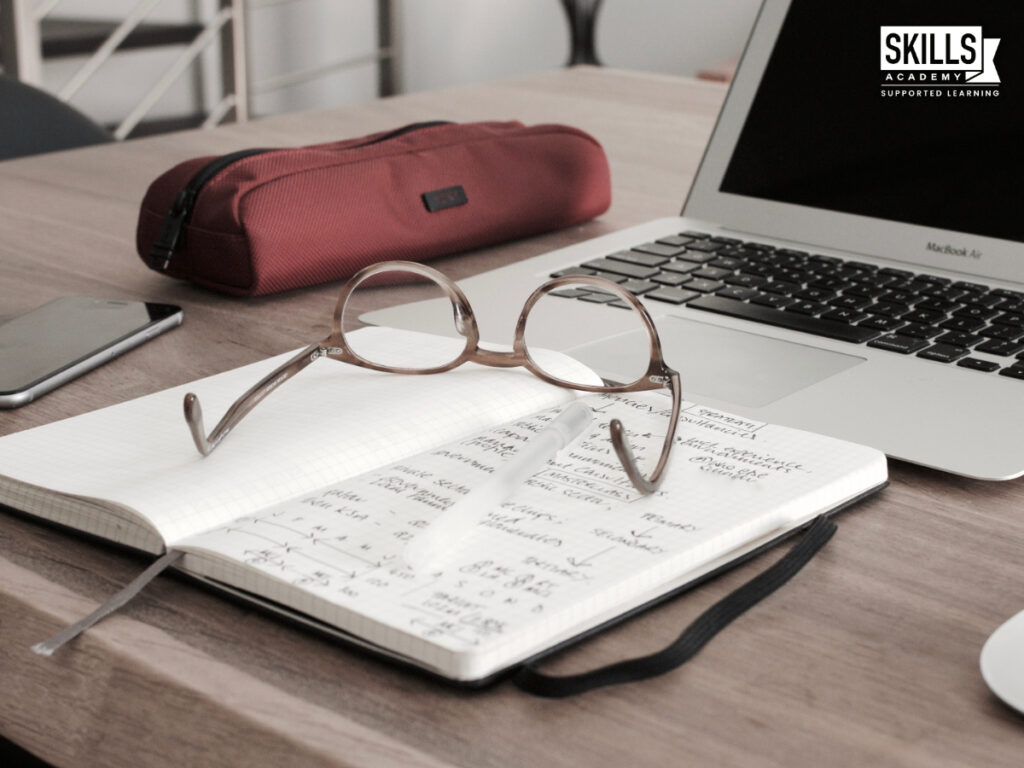 Notebook and glasses in front of a laptop. Benefits of Studying Accounting.