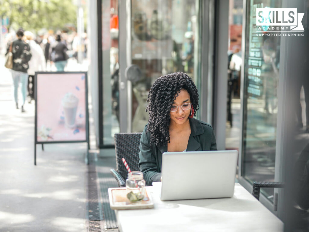 Young woman studying Western Cape business management courses outside at a coffee shop. Enrol with us today!