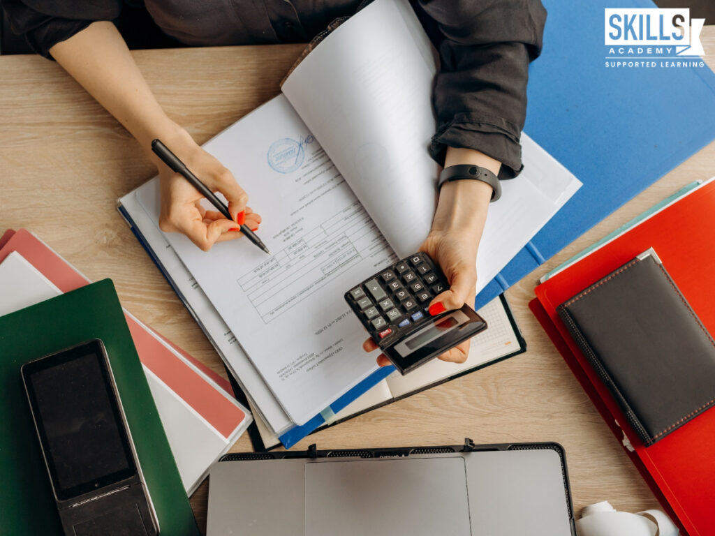 A student using a calculator and writing in a notebook. Is Accounting a scarce skill? Find out more right here. Study our courses today!