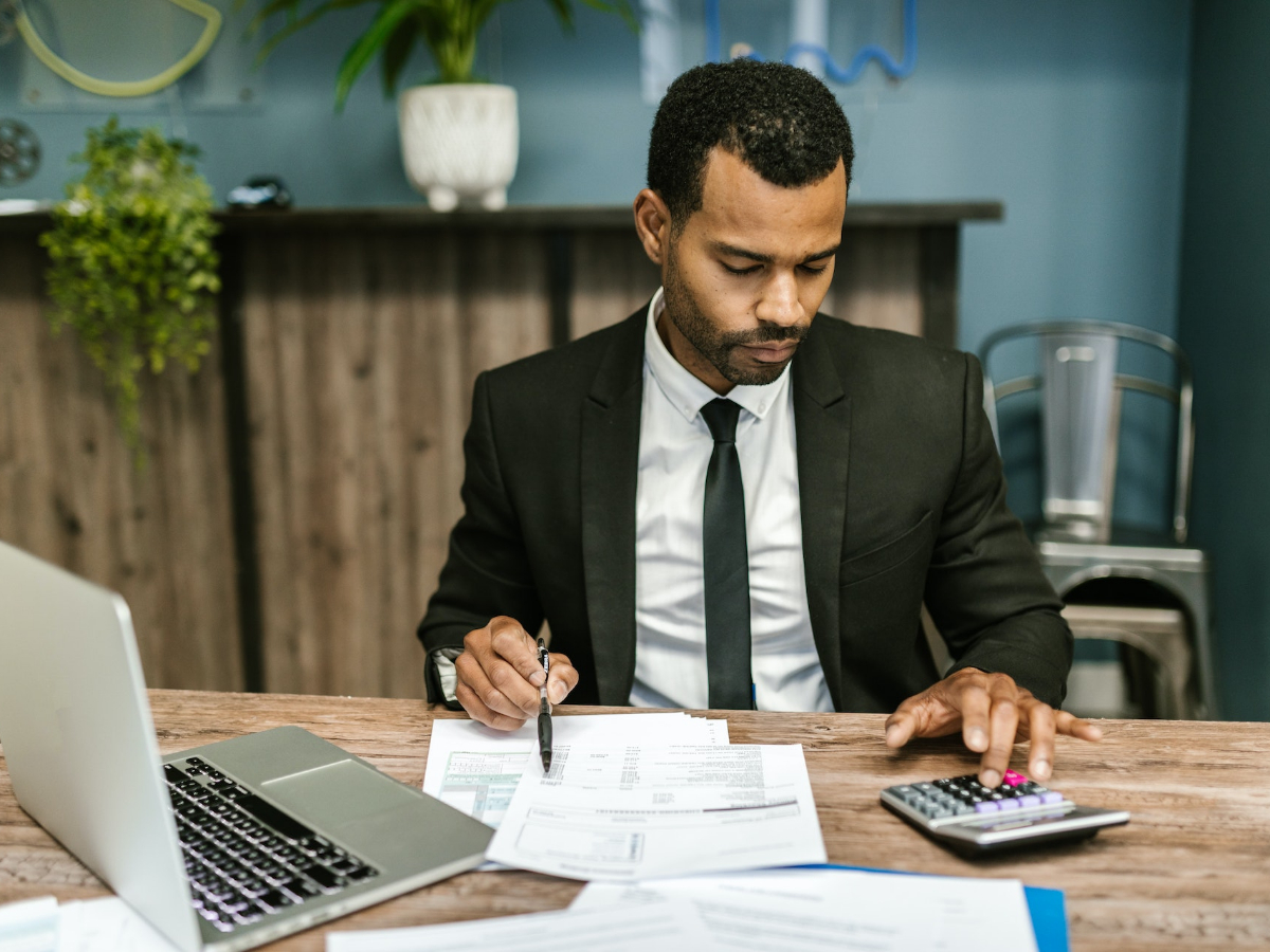 Accountant sitting at a desk and checking financial data on a sheet using a calculator. Take a look at where to study accounting and update your skills today.